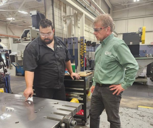 A Career Ready Participant at Cavalier's Plant 2 showing Richard Janik a workpiece he has been assembling.